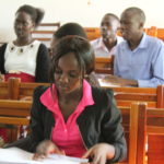 Students at Uganda Martyrs University, young woman in foreground, two young men and one young woman in backhground