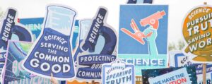 A number of posters held up at a protest march advocating for science for the common good