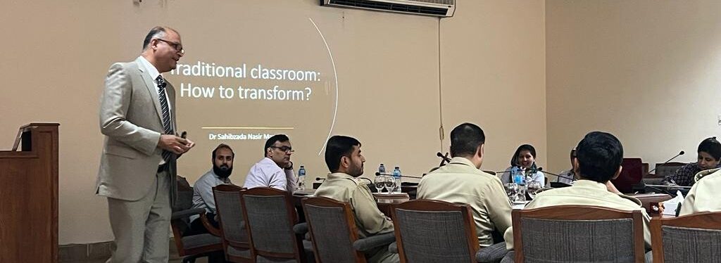 Nasir Mansoor facilitating a workshop in a room with several people, both men and women