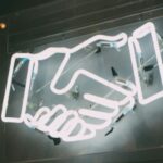 A neon sign of two shaking hands