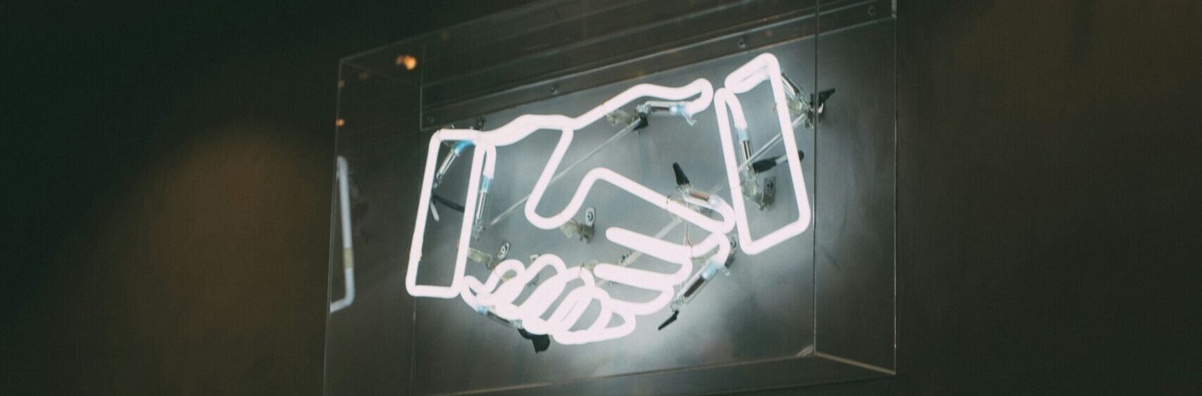 A neon sign of two shaking hands