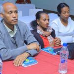 A group of Ethiopian workshop participants sitting at a table, looking forward at their facilitator